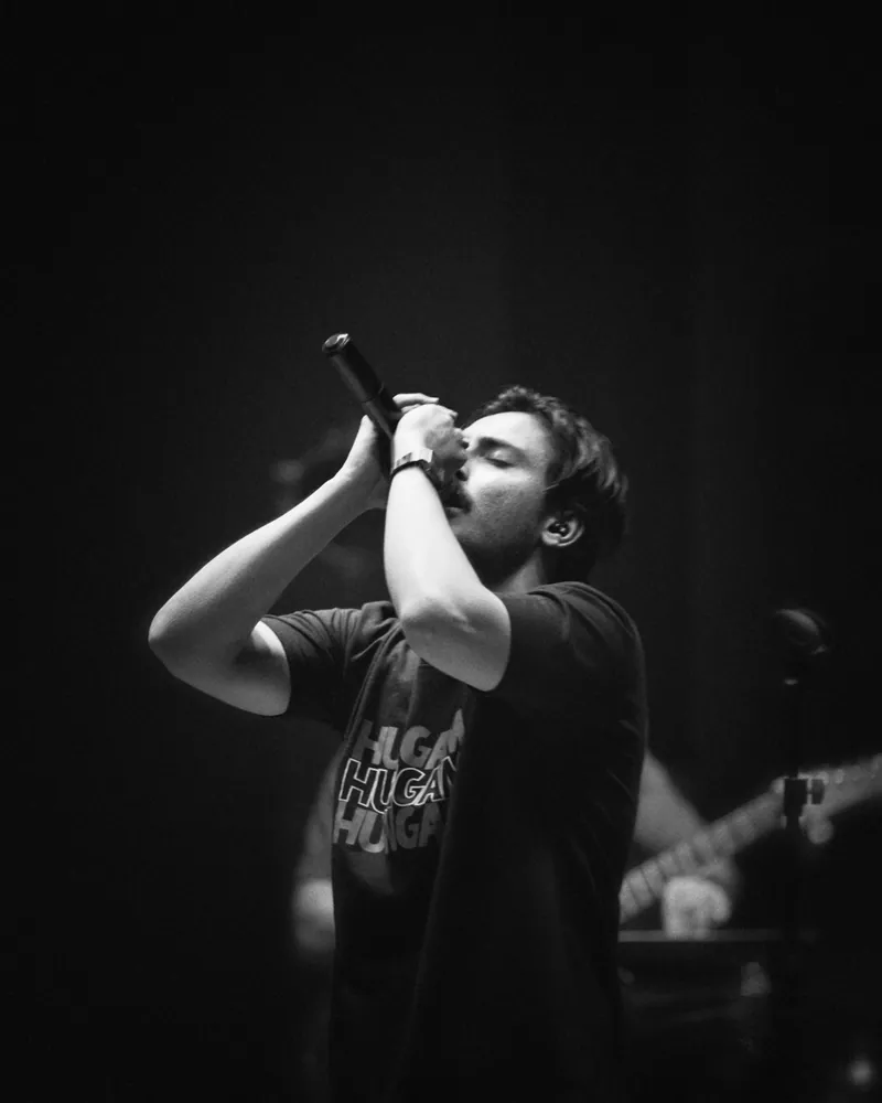 Black and white photo of Hasan Raheem singing with both hands on the mic
