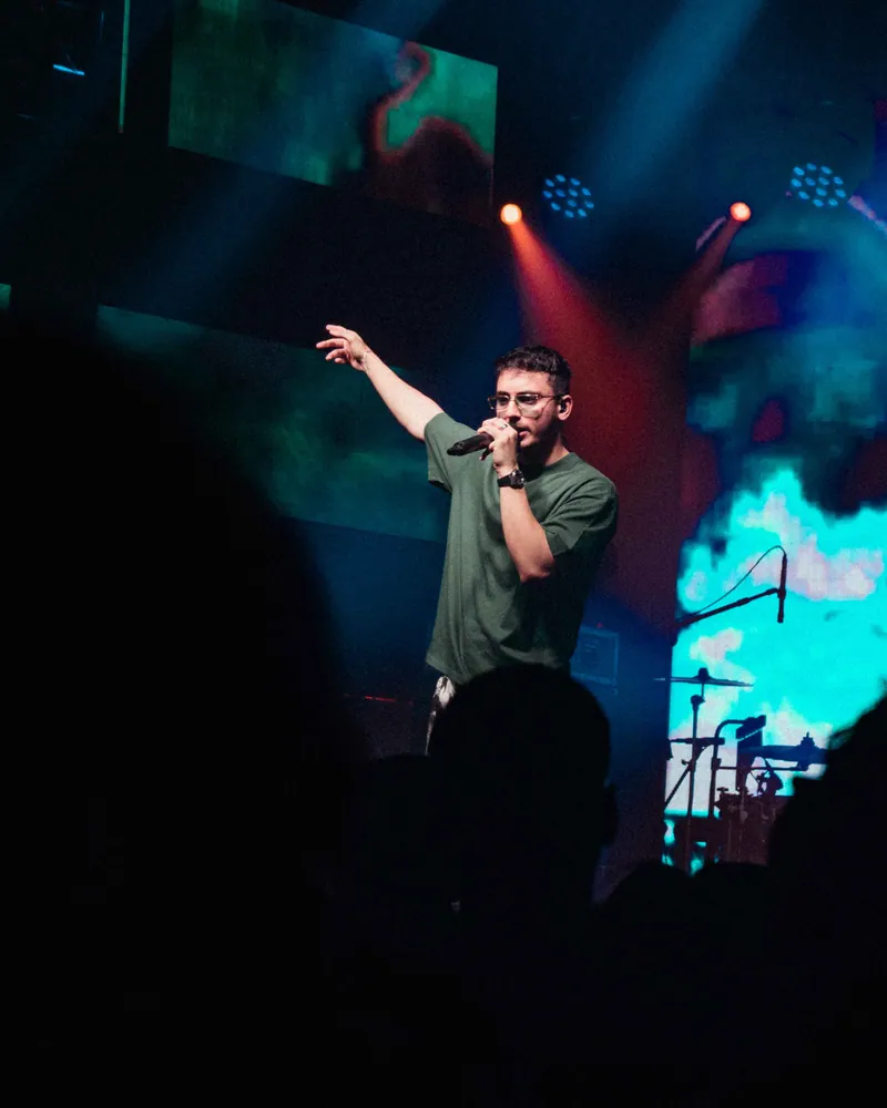 Hasan Raheem performing under teal and red stage lights